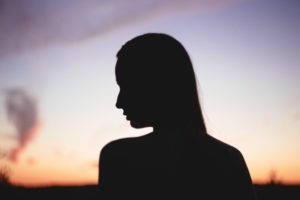 Silhouette of a woman in front of a sunset.