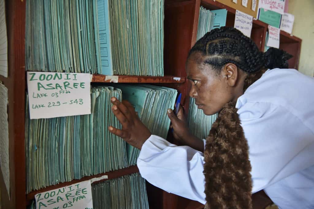 A health extension worker draws a family folder from the shelves. MEASURE Evaluation works to address the multiple factors that affect routine health information system performance.