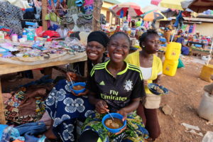 Adolescent girls in a market in Guinea take a break to eat. Photo credit: Sarah Hogan