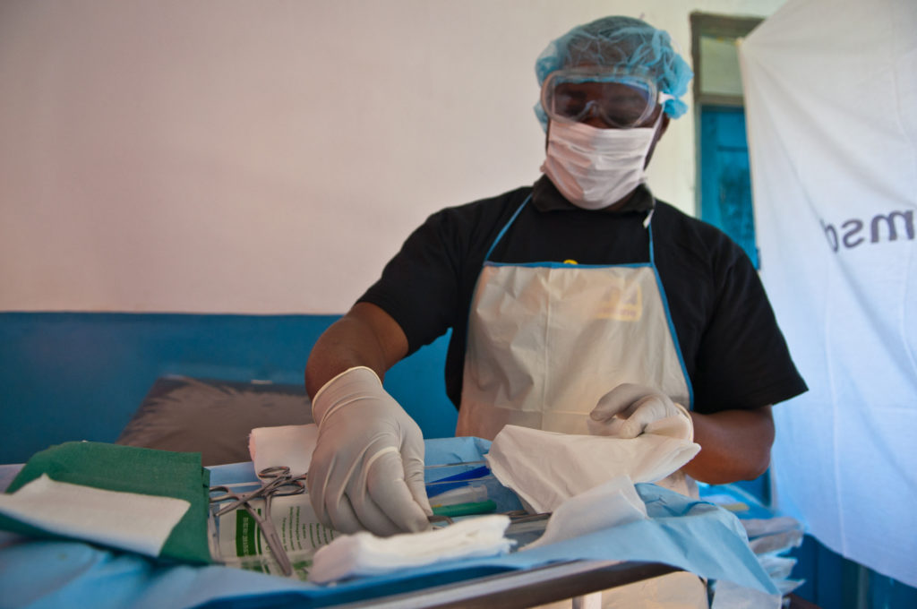 A health care worker wears PPE while handling sterile medical instruments.