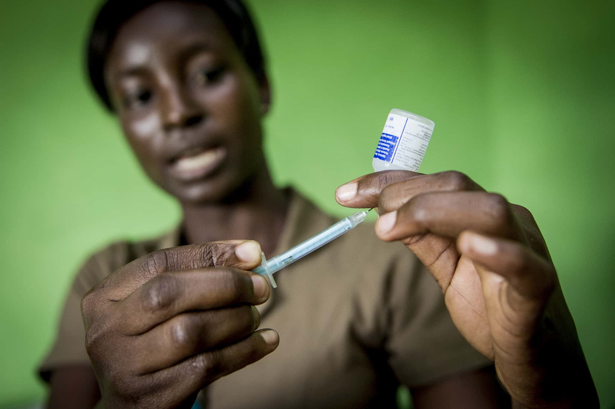 A nurse in Ghana loads a vaccine for a baby.