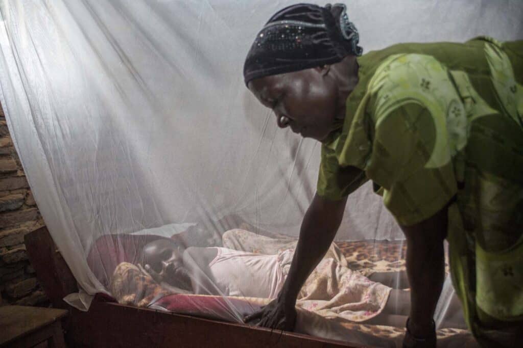 Kasifa Nakilima shows her children how to tuck in a net before sleeping in their bed at her home in Nalukelo village, Bulage Sub County, Namutumba district on 5th May 2024 “Before PMI came in, we would be falling sick all the time. If not adults then the children. We spent most of our money in treating malaria in the clinics. Whenever my husband would run out of money he would become violent. We would always quarrel. But these days we know how to prevent malaria. We save money and home is peacefull” she said. Namutumba district in Busoga region is one of the high malaria burden districts. Through VHTs, PMI has supported the district in training communities in malaria management, the staff in records and malaria commodity stock management. Photo by Jimmy Adriko