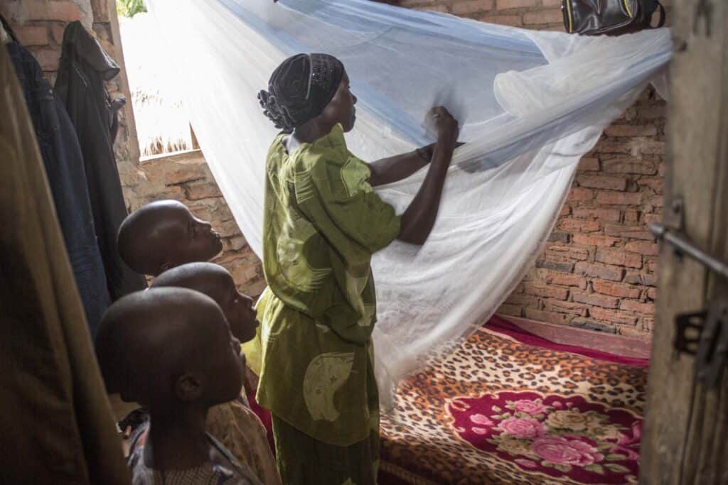 Kasifa Nakilima shows her children how to tuck in a net before sleeping in their bed at her home in Nalukelo village, Bulage Sub County, Namutumba district on 5th May 2024 “Before PMI came in, we would be falling sick all the time. If not adults then the children. We spent most of our money in treating malaria in the clinics. Whenever my husband would run out of money he would become violent. We would always quarrel. But these days we know how to prevent malaria. We save money and home is peacefull” she said. Namutumba district in Busoga region is one of the high malaria burden districts. Through VHTs, PMI has supported the district in training communities in malaria management, the staff in records and malaria commodity stock management. Photo by Jimmy Adriko