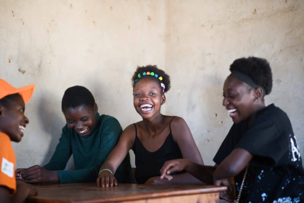 A group of young women and girls gather together for a peer counseling session at Mwanjuni Health Post.