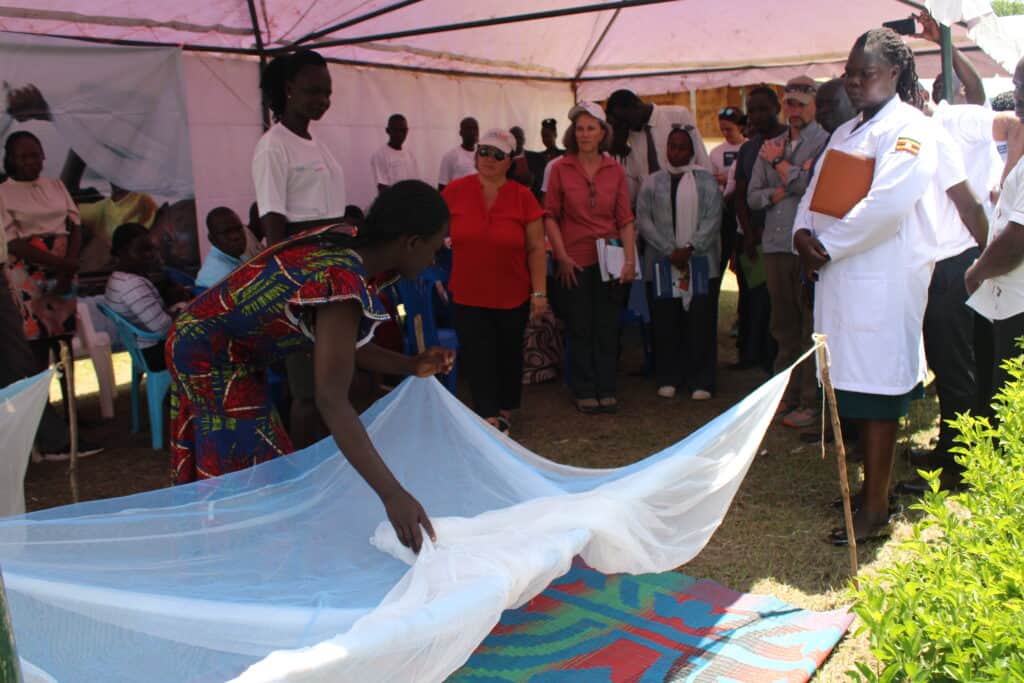 A woman demonstrates how a mosquito net is used to prevent malaria.