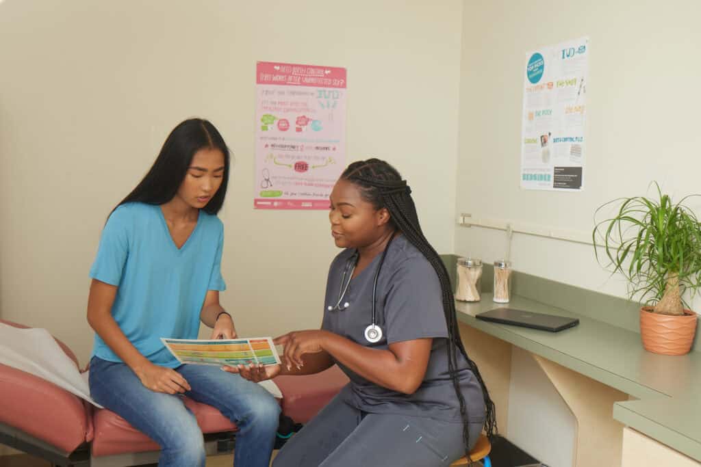 A nurse discusses literature with a patient in an examination room