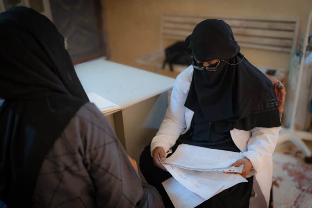 A Yemeni midwife sits and reviews paperwork.