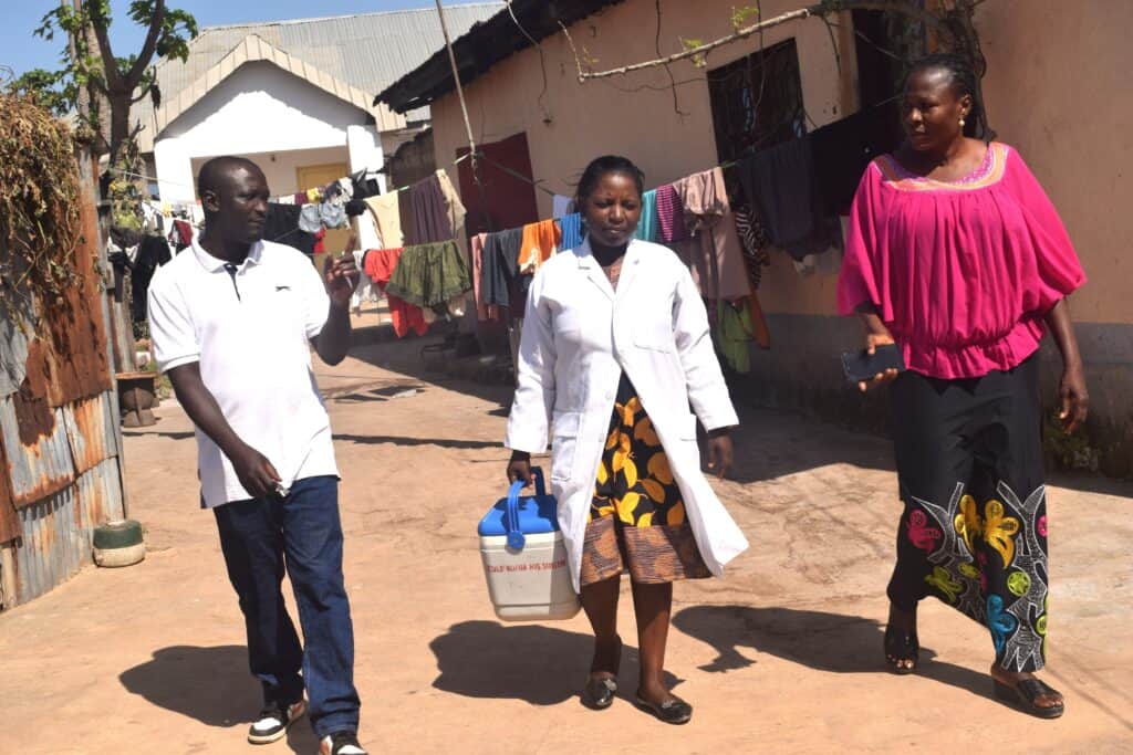 Community leader Michael Nyam Sila (left) walking with nurses to an HPV vaccination point.